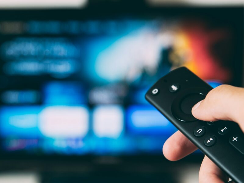 Hand using a streaming TV remote for programmatic CTV advertising