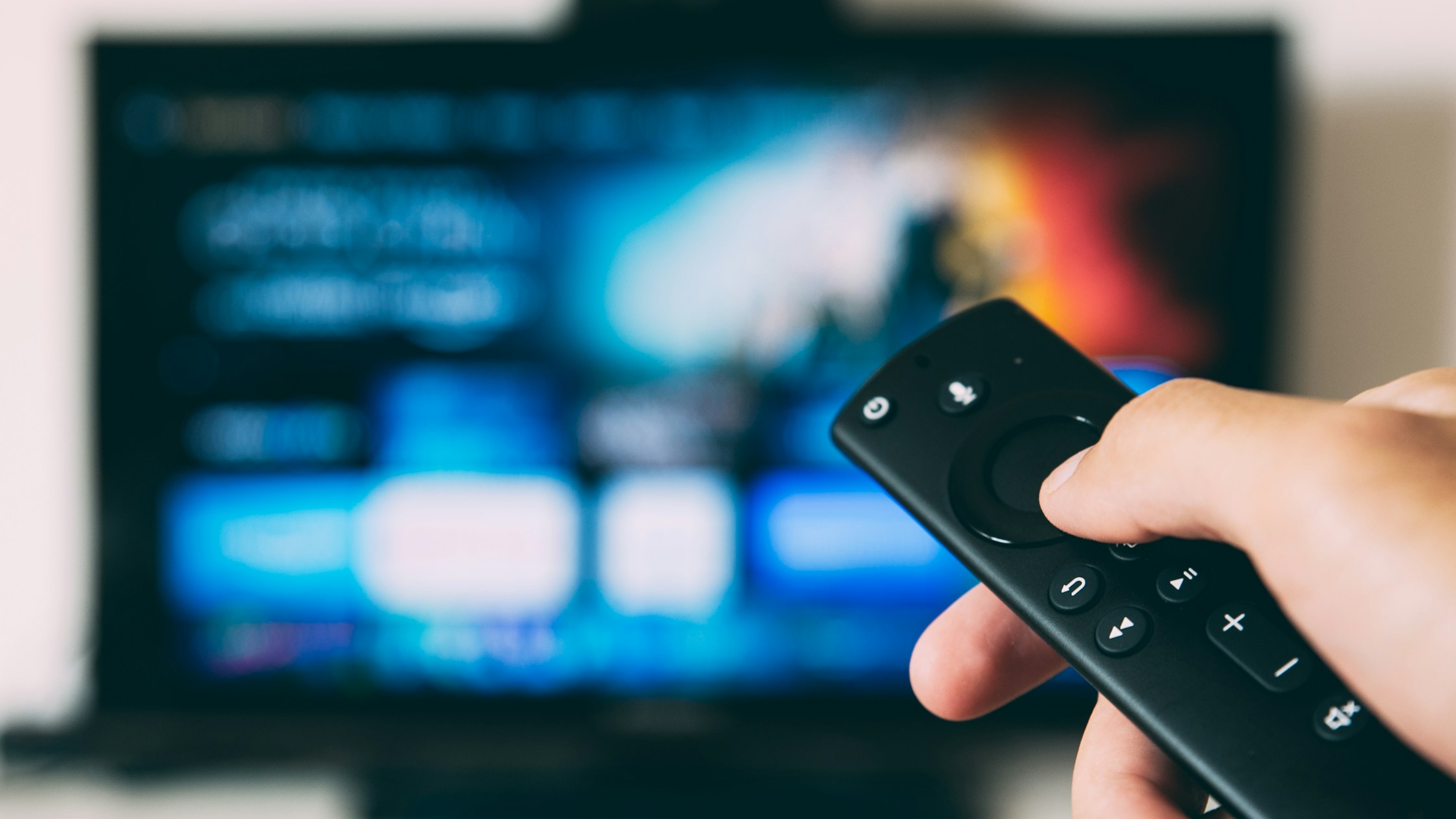 Hand using a streaming TV remote for programmatic CTV advertising